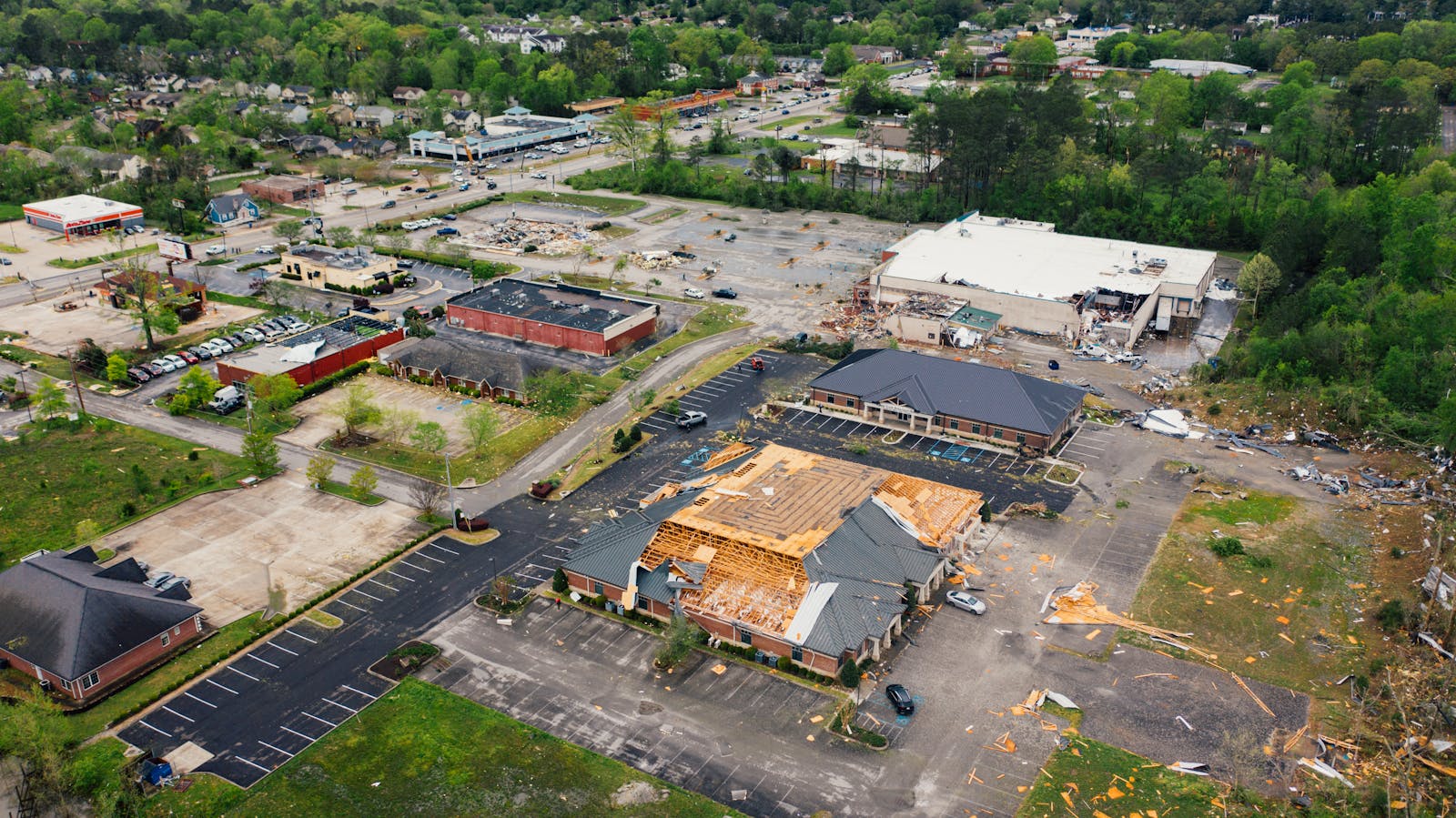 Aerial view of terrible consequences of thunderstorm on small town buildings with ruined roof and uprooted trees
