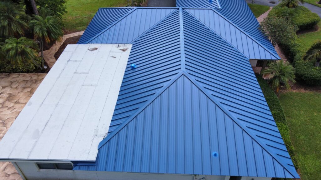 Aerial view of a partially completed blue standing seam metal roof with exposed underlayment on a Greenacres home