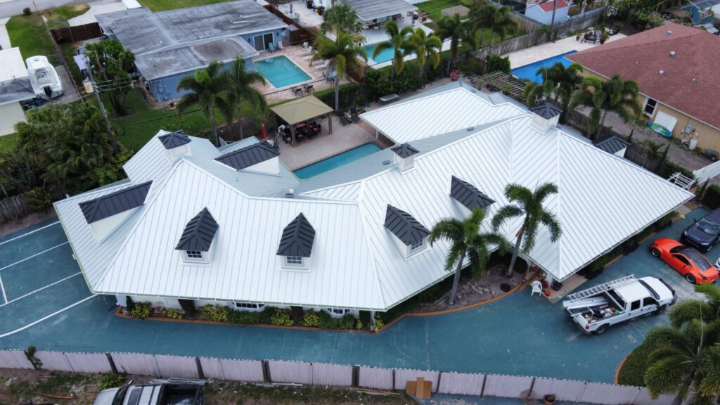 Aerial view of a large white standing seam metal roof with multiple dormers on a home in Greenacres, Florida